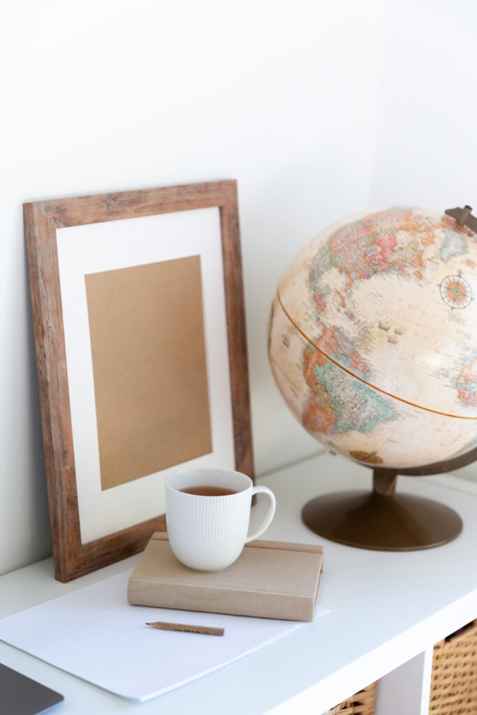 15 Neutral Office Decor Ideas That Feel Calm, Curated, and Intentional neutral office shelf styling with framed art, decorative globe, stacked books, and ceramic mug