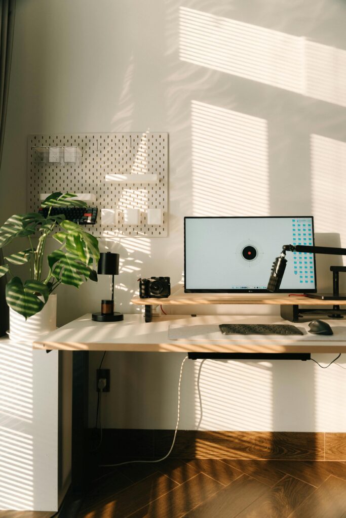 15 Neutral Office Decor Ideas That Feel Calm, Curated, and Intentional sunlit neutral office workspace with warm wood desk, indoor plant, and soft beige tones
